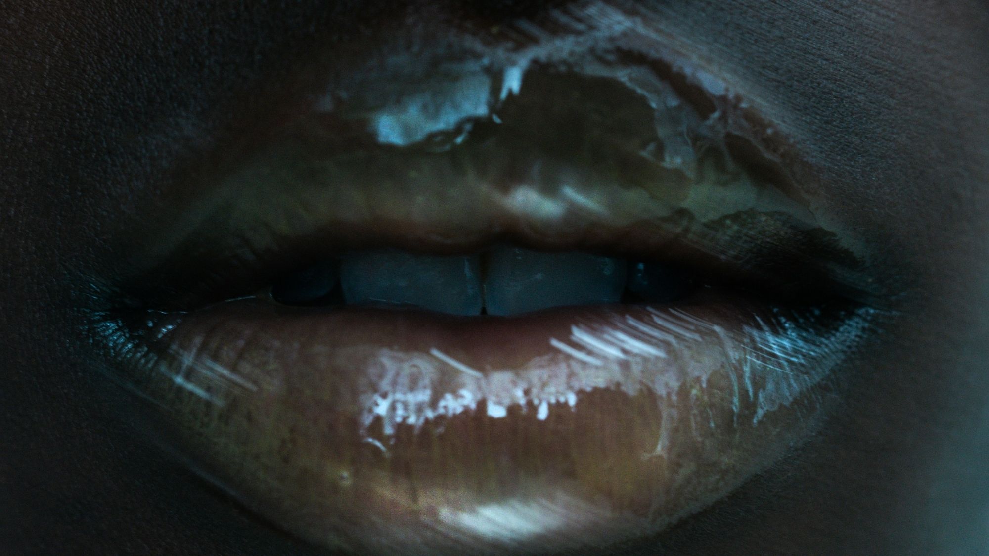 Extreme close-up of glossy lips under moody lighting, evoking sensual symbolism and future-facing identity aesthetics.