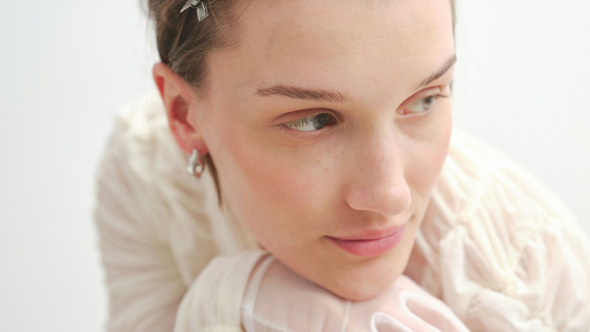 Close-up portrait of woman in ruched ivory mesh top and gloves, styled for Soft Rebellion by C2 Fashion Studio.