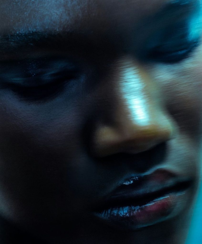Abstract close-up portrait of a person in blue lighting, symbolizing future mythologies and fragmented global culture.