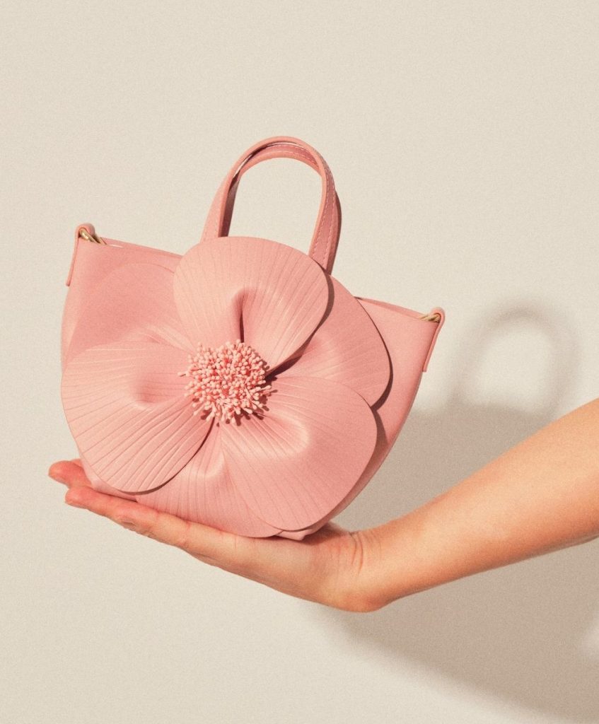 Pink handbag shaped like a flower, held in a hand, symbolizing emotional durability and meaningful design in fashion trend forecasting.