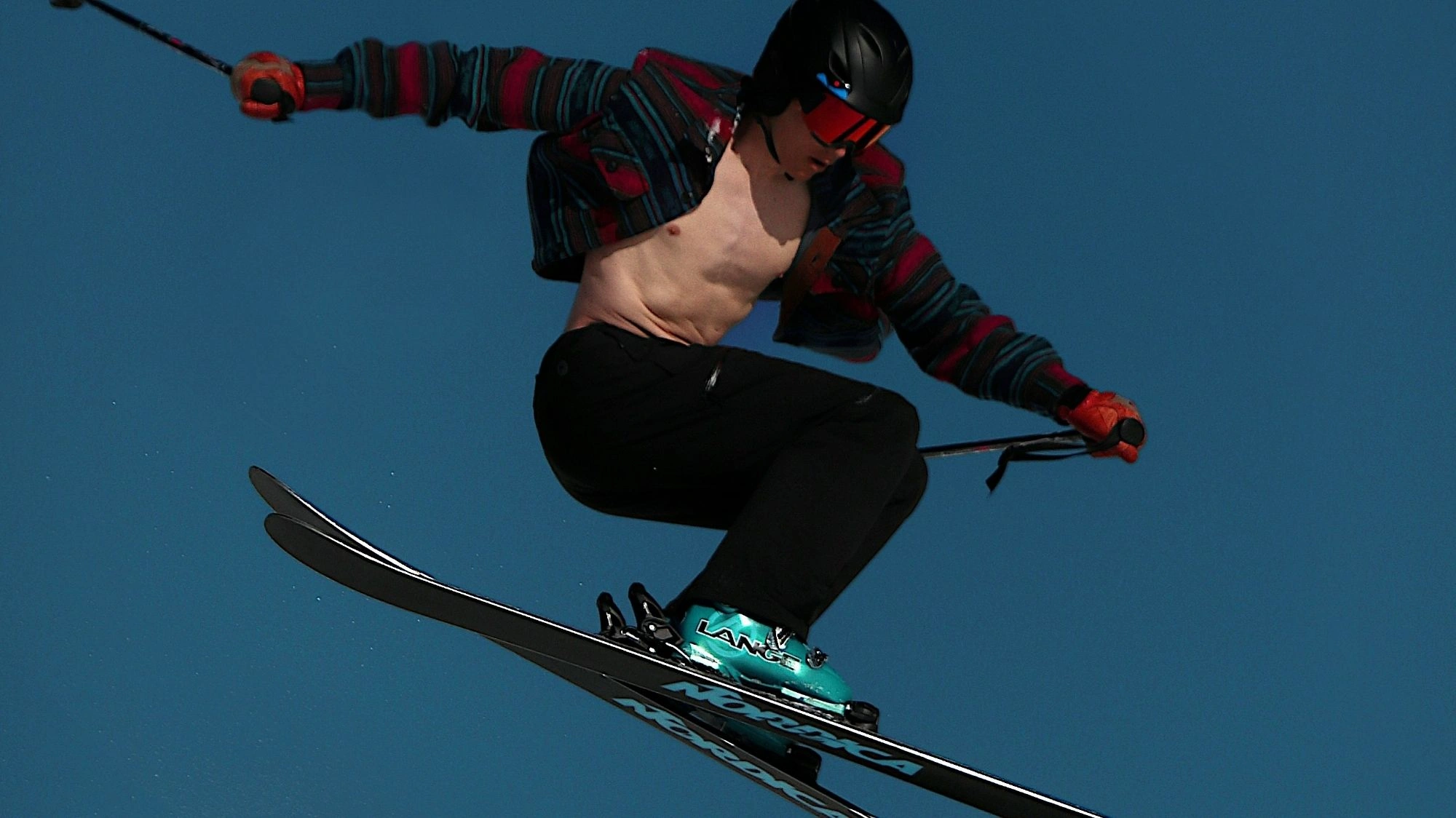 Freestyle skier in mid-air wearing striped jacket and goggles — a dynamic shot for a trend forecasting tool for influencers and creators.