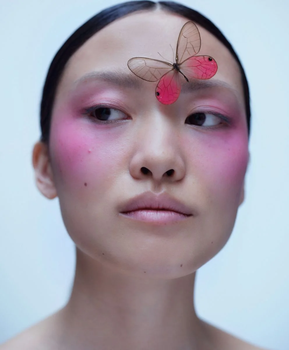 Model with pink blush and butterfly on forehead representing visionary beauty and customized trend forecasting