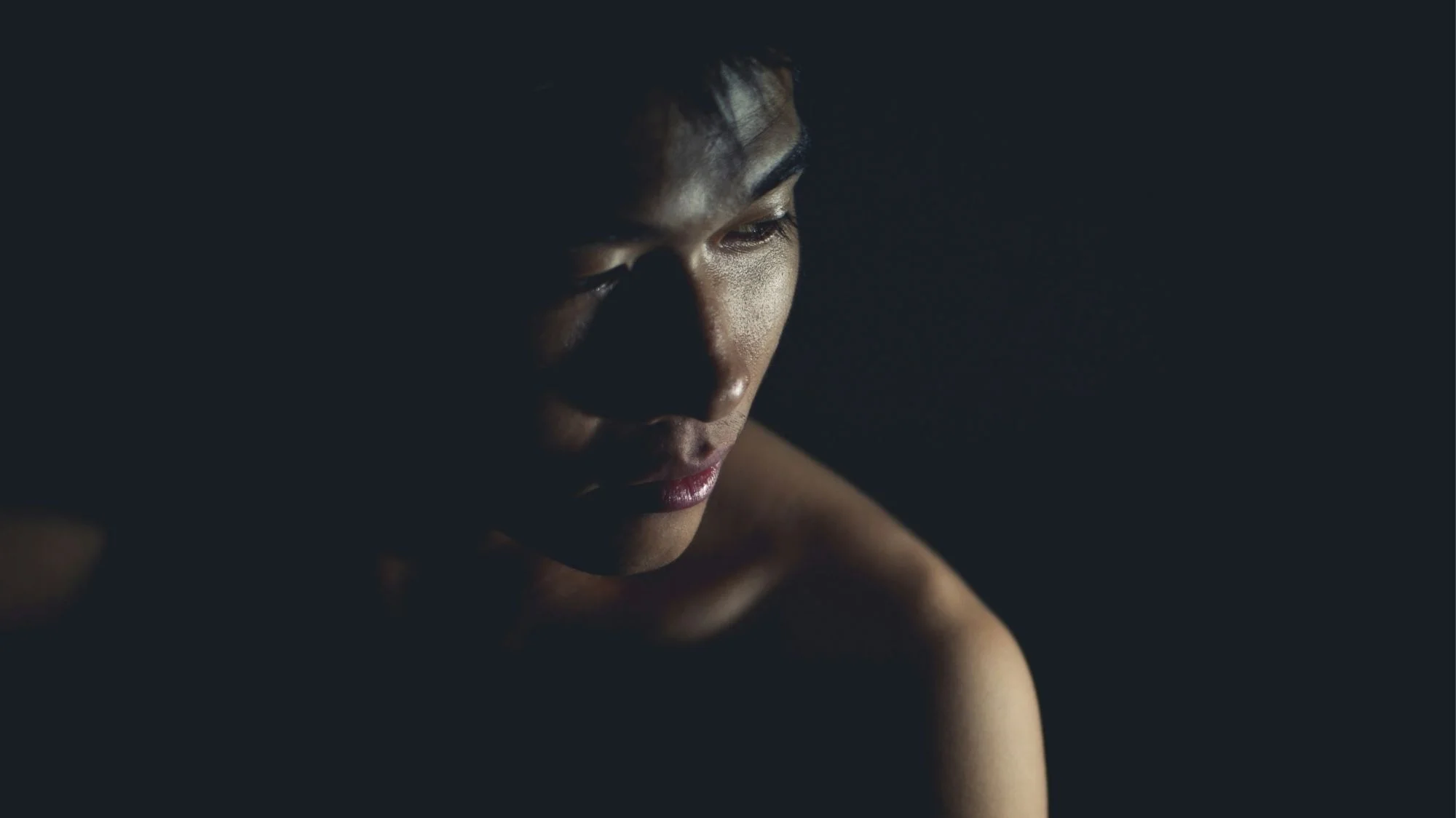 Moody portrait of a model in low light, symbolizing Autumn Winter 2026 2027 fashion trend forecasting with themes of sensory revival, emotional resilience, and introspection.