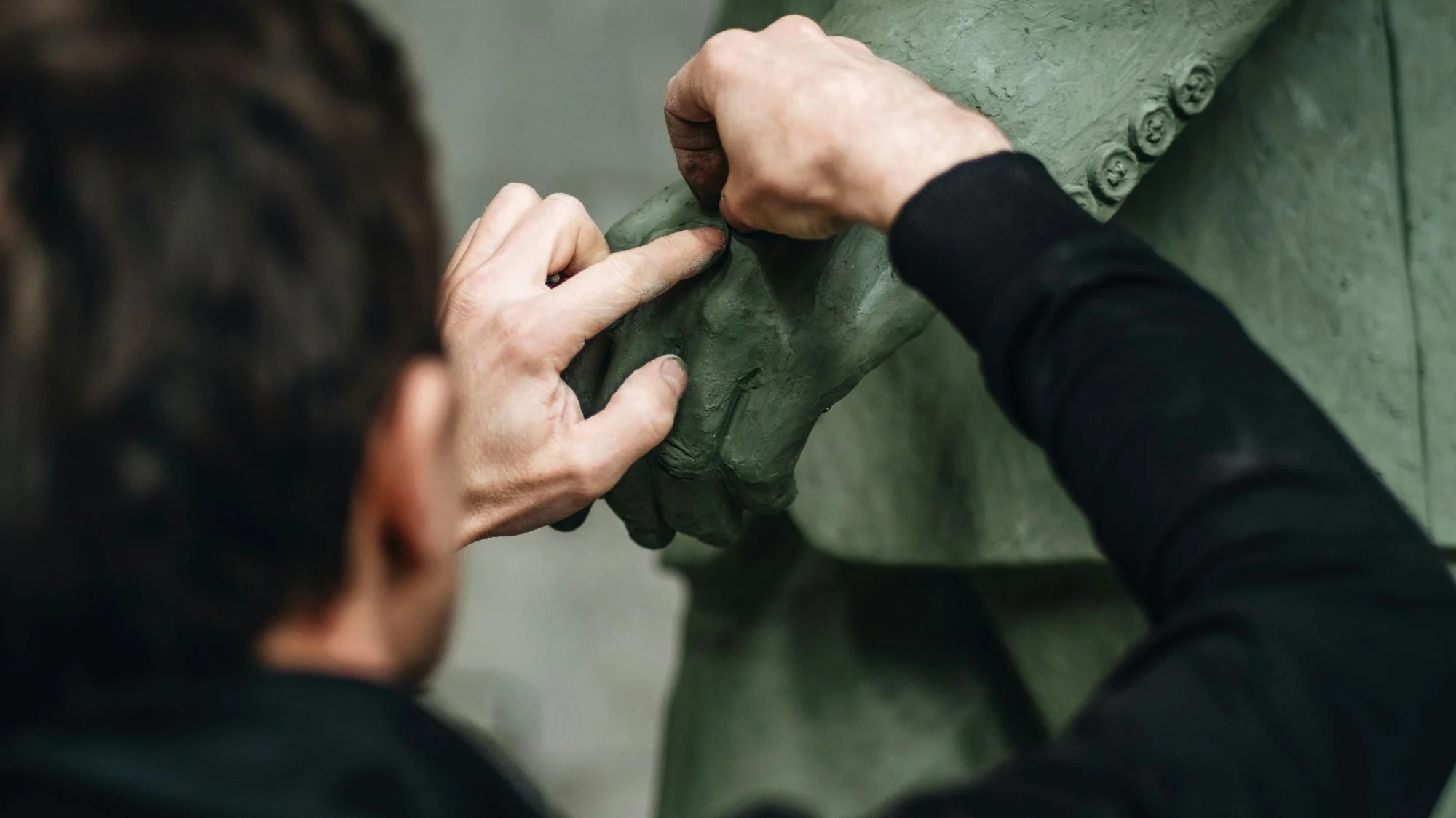 Close-up of artisan hands sculpting details on a garment-like form, symbolizing emotional durability through storytelling, surface, memory, and repair in fashion. Concept curated by C2 Fashion Studio, a leading trend forecasting agency.