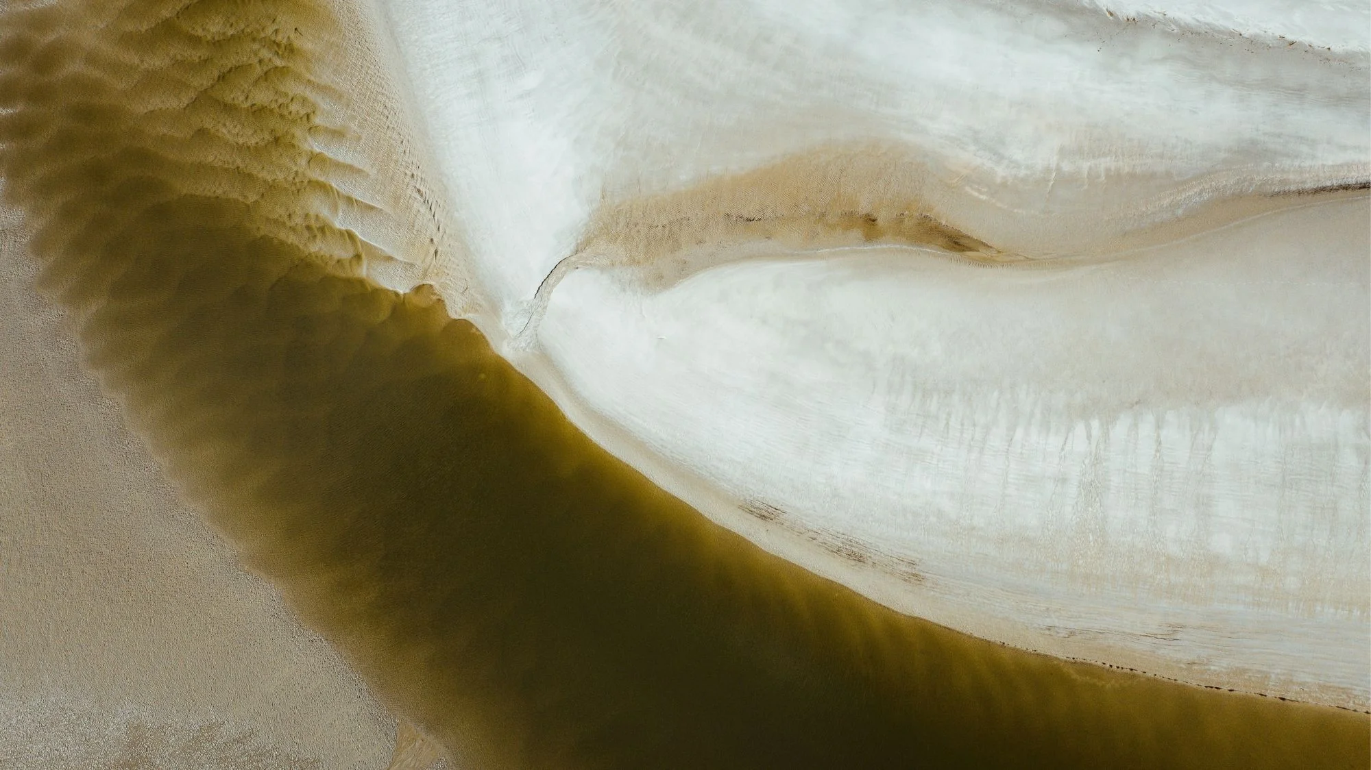 Abstract aerial view of sand and water textures in neutral tones, symbolizing Autumn Winter 2026 2027 fashion trend forecasting with themes of sensory revival, tactility, and future fashion trends.