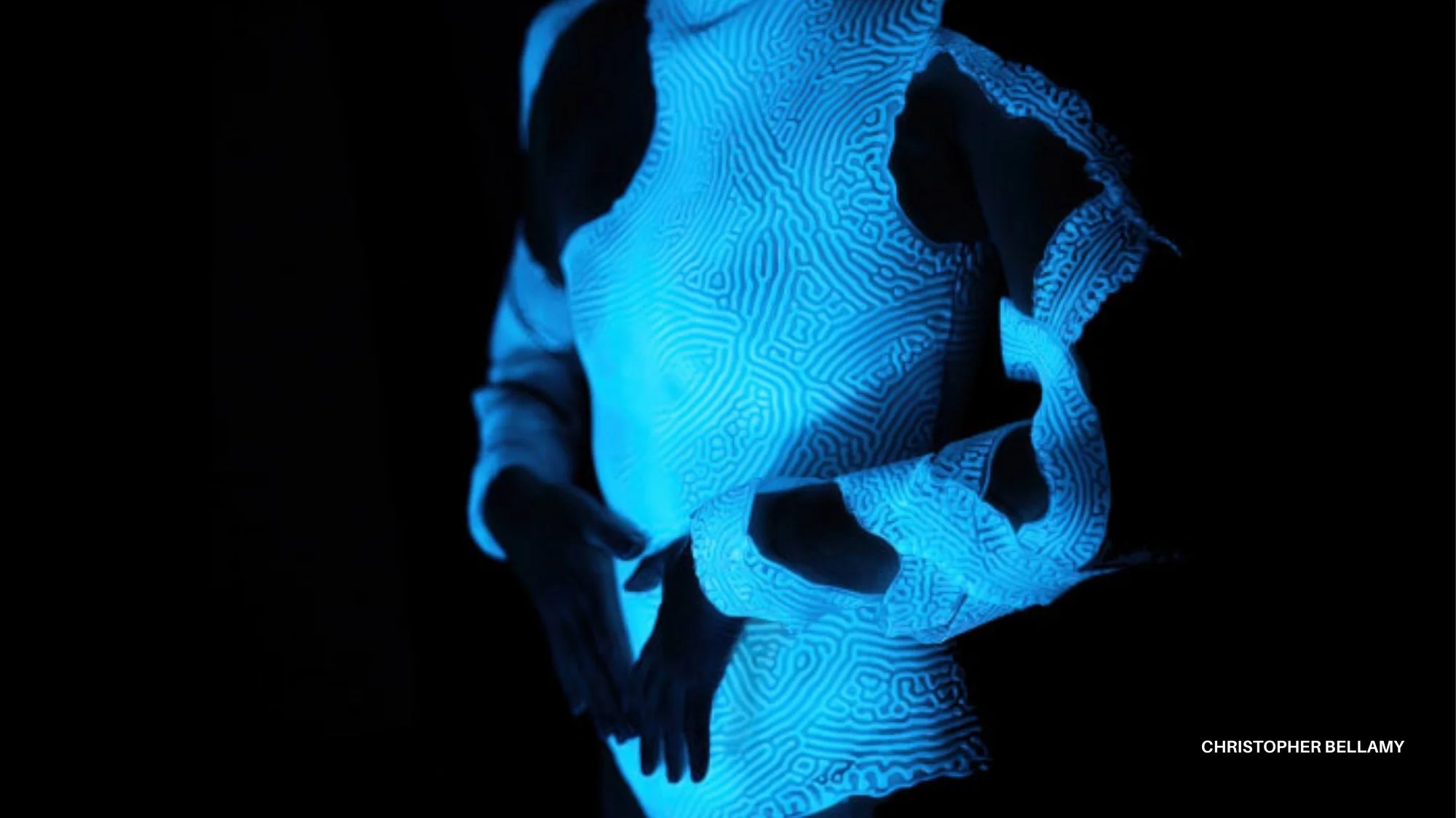 Glowing blue futuristic garment with intricate circuit-like patterns in the dark, symbolizing innovation, technology, and future fashion trends explored by C2 Fashion Studio.