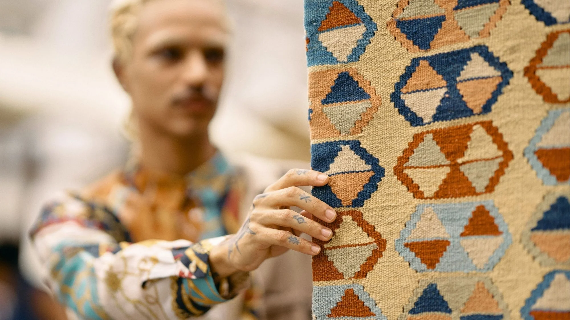 Close-up of artisan holding a handwoven textile with geometric patterns, symbolizing craftsmanship and the Sense of Place fashion trend forecast for Autumn Winter 2026 2027 by C2 Fashion Studio, a trend forecasting solution.
