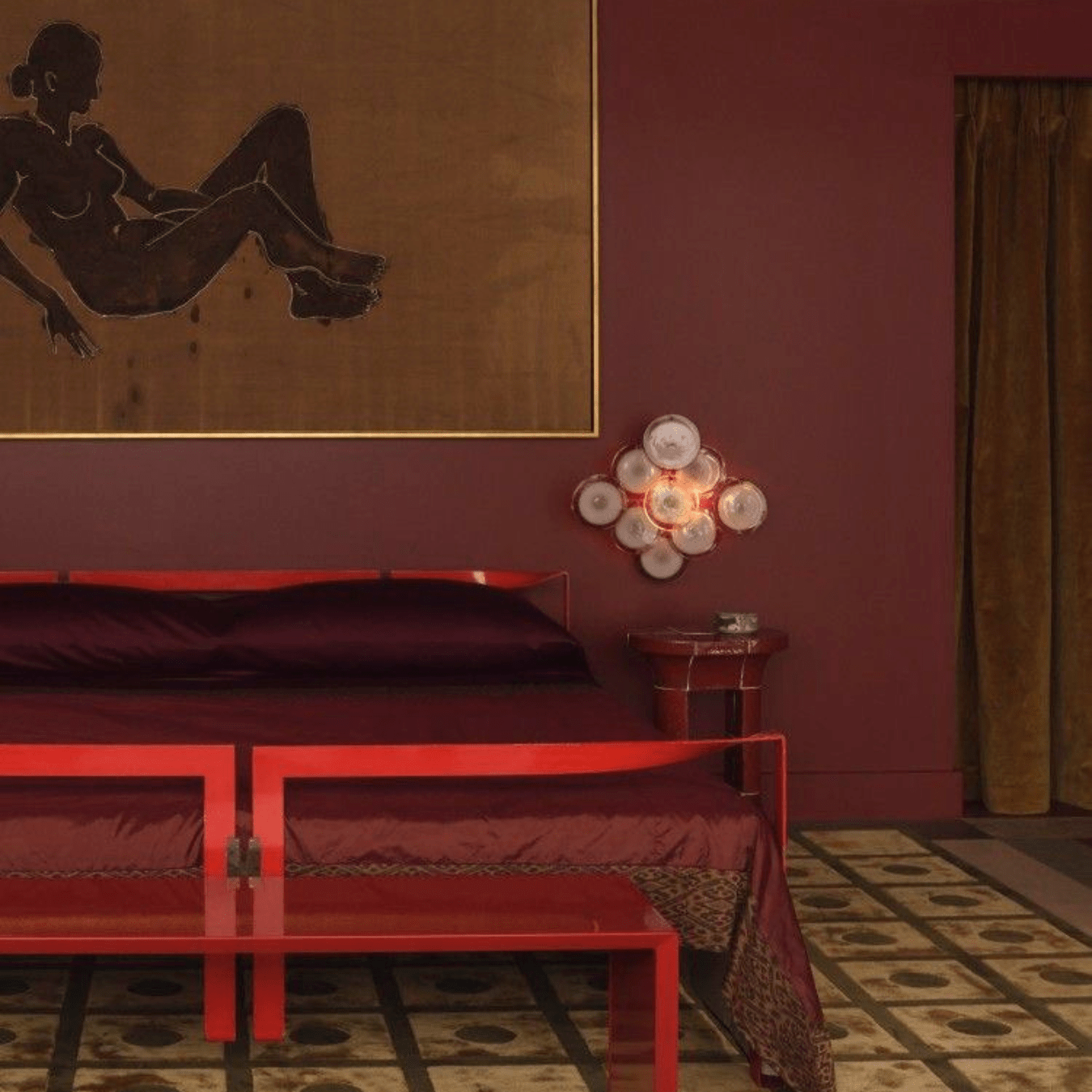 Luxurious burgundy and red bedroom interior with modern artwork and moody lighting, symbolizing Autumn Winter 2027 2028 interior design and fashion trend forecasting themes of quiet opulence and cultural memory.