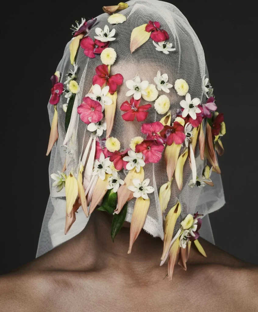 Model wearing a veil of white mesh adorned with colorful flowers, symbolizing Organic Thinking Design Strategies in fashion forecasting by C2 Fashion Studio.