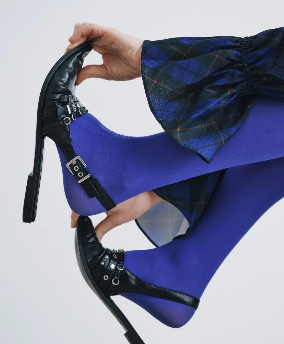 Close-up of bold fashion styling with electric blue tights, black heels, and checkered sleeves, representing innovative design insights from C2 Fashion Studio, a trend forecasting agency providing fashion trend solutions.