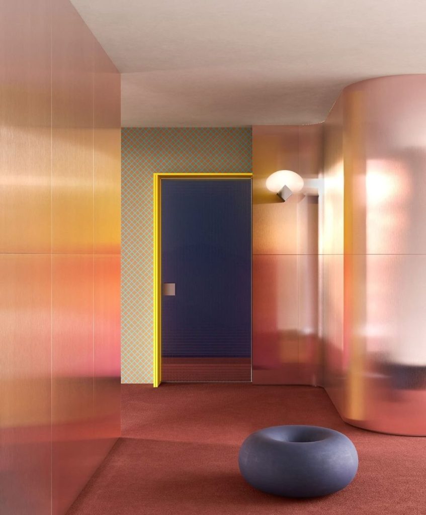 Colorful interior design space with gradient metallic panels and sculptural furniture representing Sensorial Boundaries, the Creative Innovation Trend for Spring Summer 2027, decoded by C2 Fashion Studio’s trend forecasting platform.
