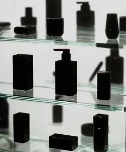 Minimalist black skincare and wellness containers displayed on glass shelves, symbolizing longevity culture, science-driven vitality, and future wellness aesthetics explored by C2 Fashion Studio.