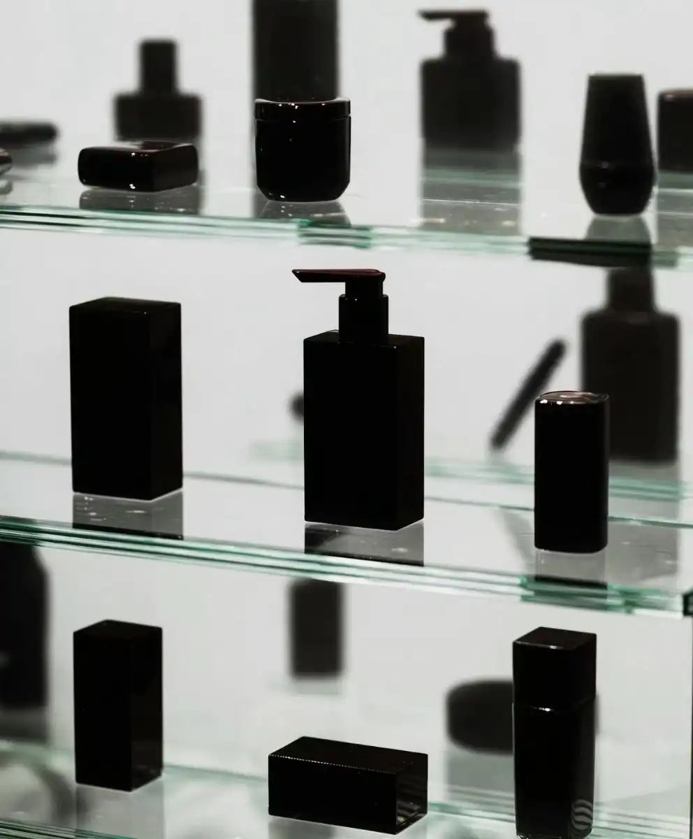 Minimalist black skincare and wellness containers displayed on glass shelves, symbolizing longevity culture, science-driven vitality, and future wellness aesthetics explored by C2 Fashion Studio.