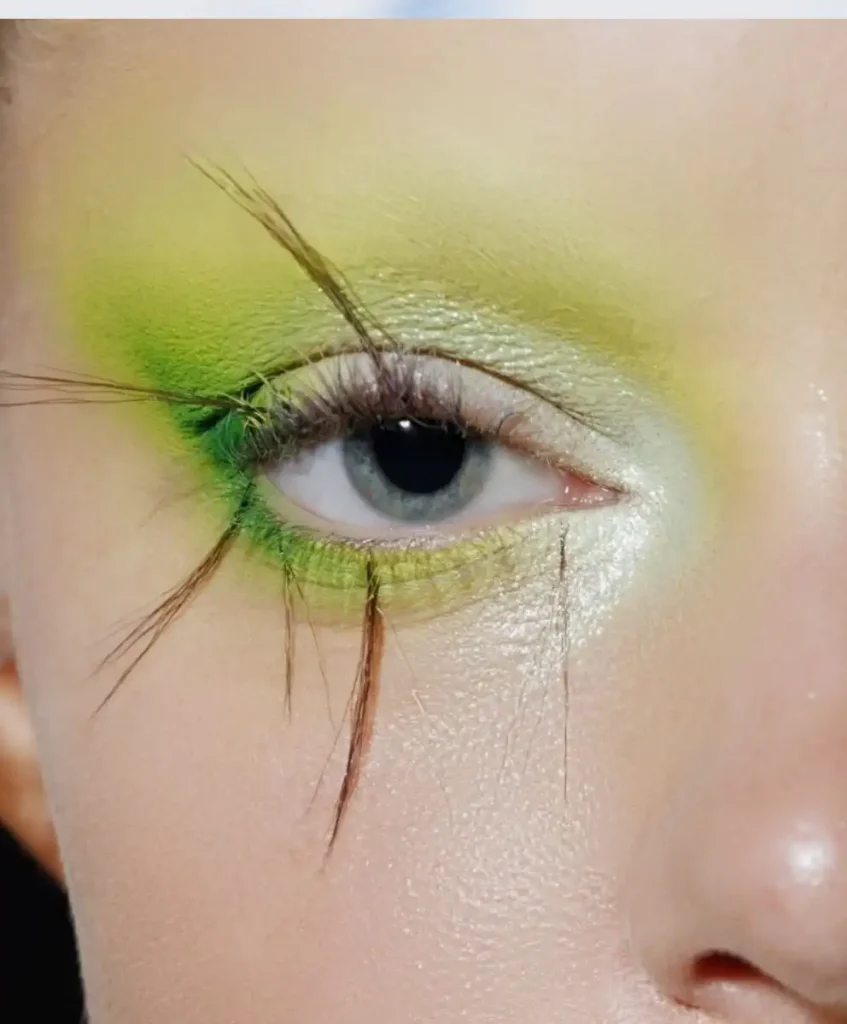 Close-up of model’s eye with yellow-green makeup and extended lashes, showcasing nature-inspired beauty and regenerative design from C2 Fashion Studio Symbiotic Futures trend forecasting agency for Spring Summer 2027.