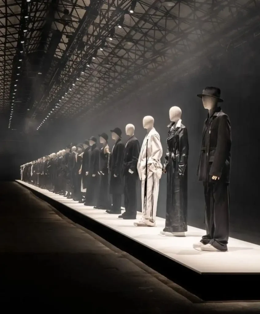 A dramatic runway installation featuring minimalist black-and-white silhouettes at a global fashion industry event, highlighting emerging AW27/28 trend directions.
