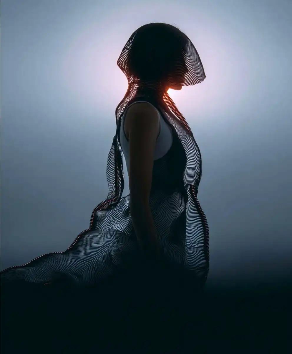 Silhouette of a model wearing a flowing, semi‑transparent advanced textile that ripples around the body, illustrating Material Intelligence and responsive fabrics for C2 Fashion Studio trend forecasting solutions.