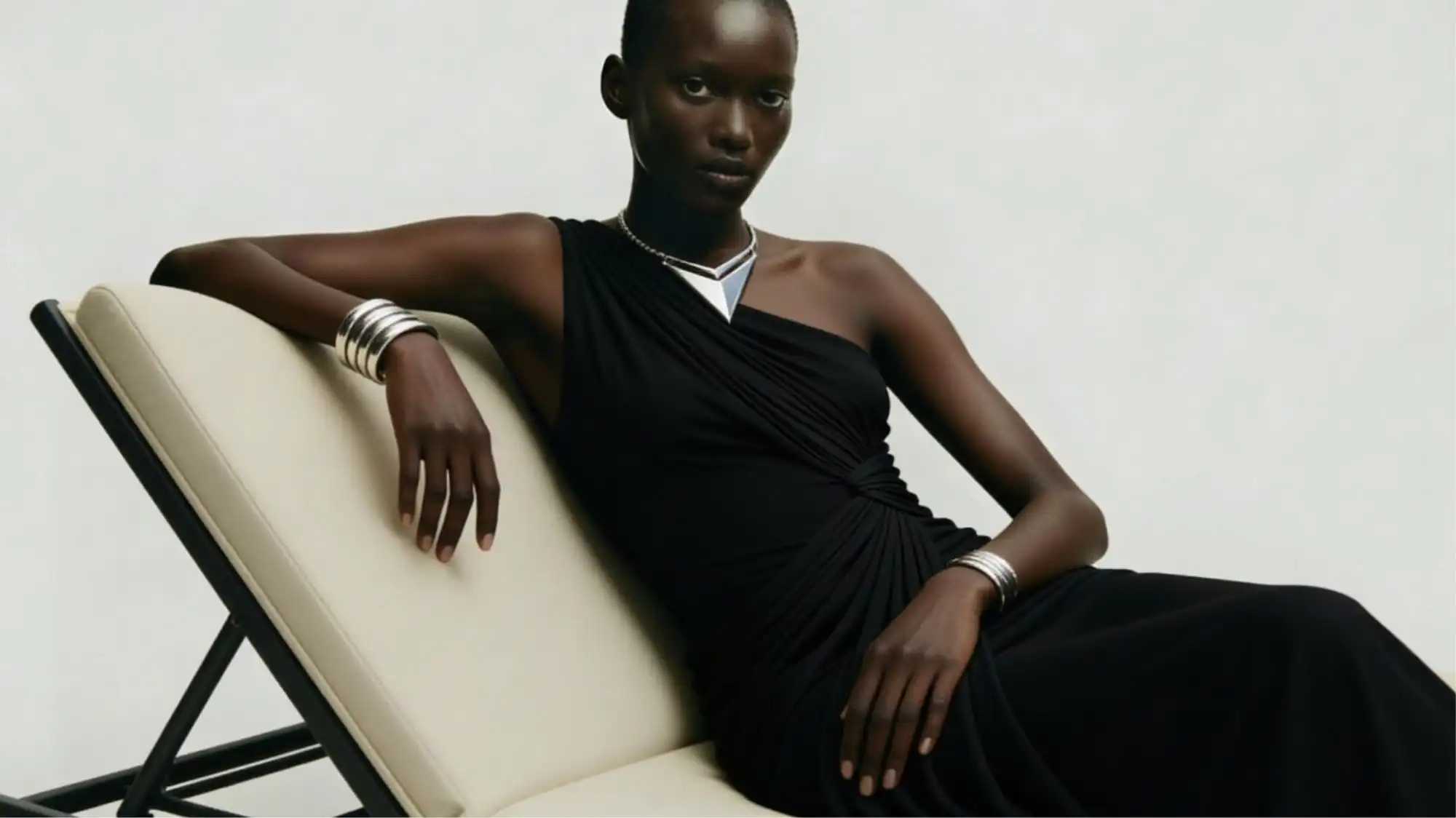 Minimal luxury fashion portrait featuring sculptural black draped eveningwear and metallic jewelry, representing Clarity Intelligence, quiet luxury, and strategic Fashion Trend Forecasting by C2 Fashion Studio.