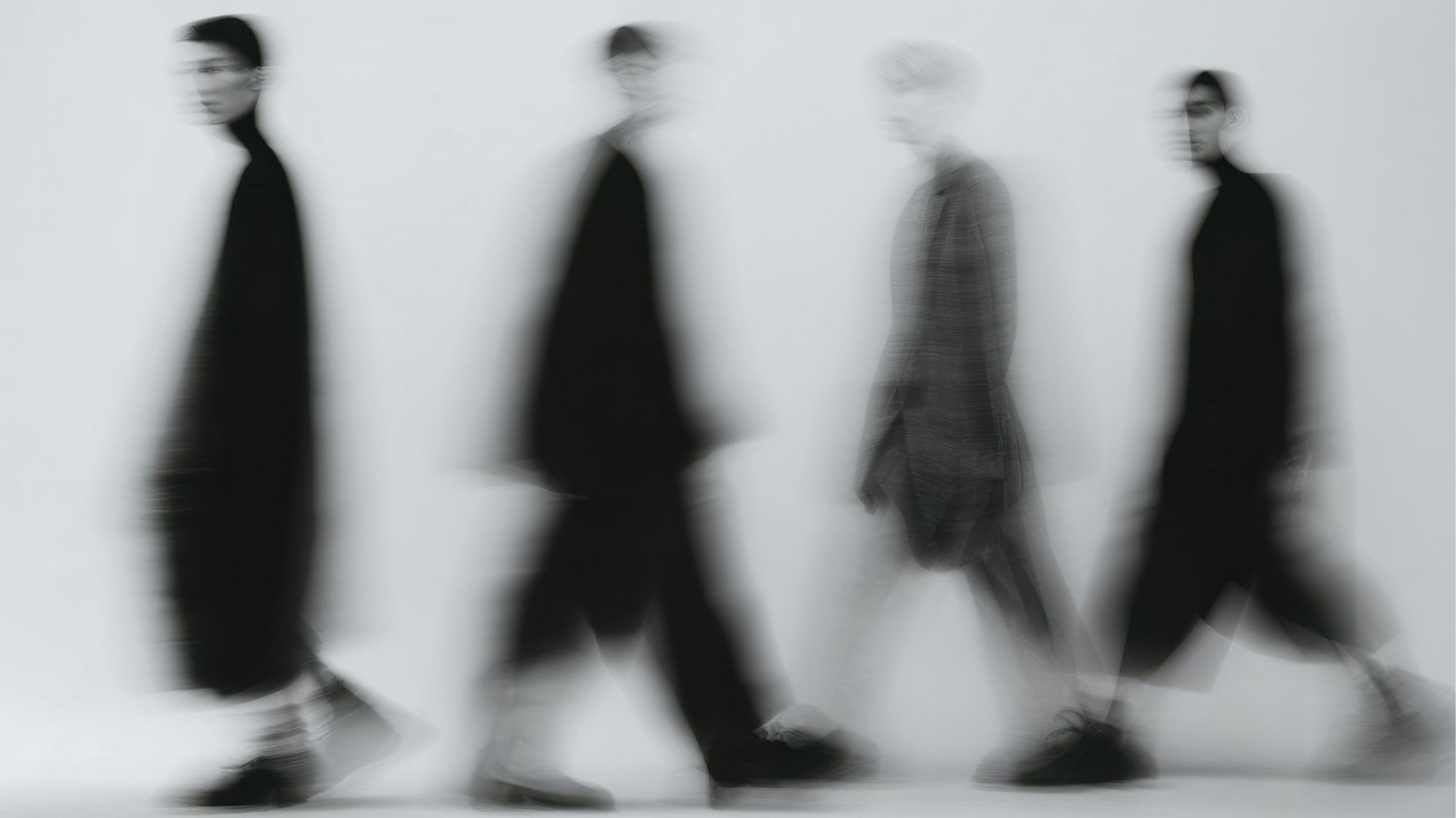 Blurred minimalist fashion silhouettes in motion featuring monochromatic tailoring and fluid movement aesthetics, representing strategic Fashion Trend Forecasting and emotionally restrained luxury for future runway direction.