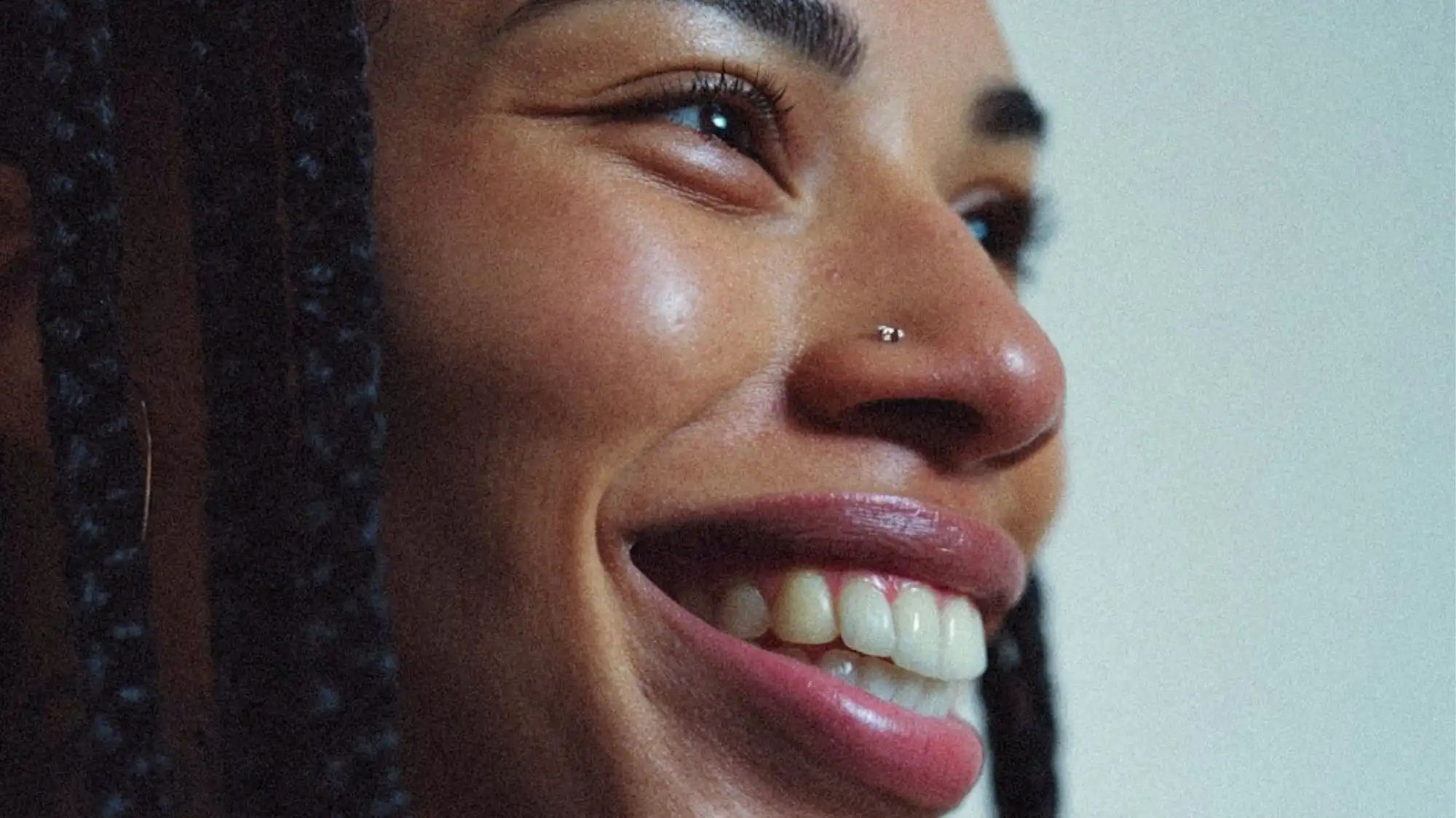 Future Consumer 2028 beauty portrait featuring natural glowing skin, braided hair, and authentic joyful expression representing emotional wellbeing, inclusive beauty, and human-centered luxury aesthetics by C2 Fashion Studio.