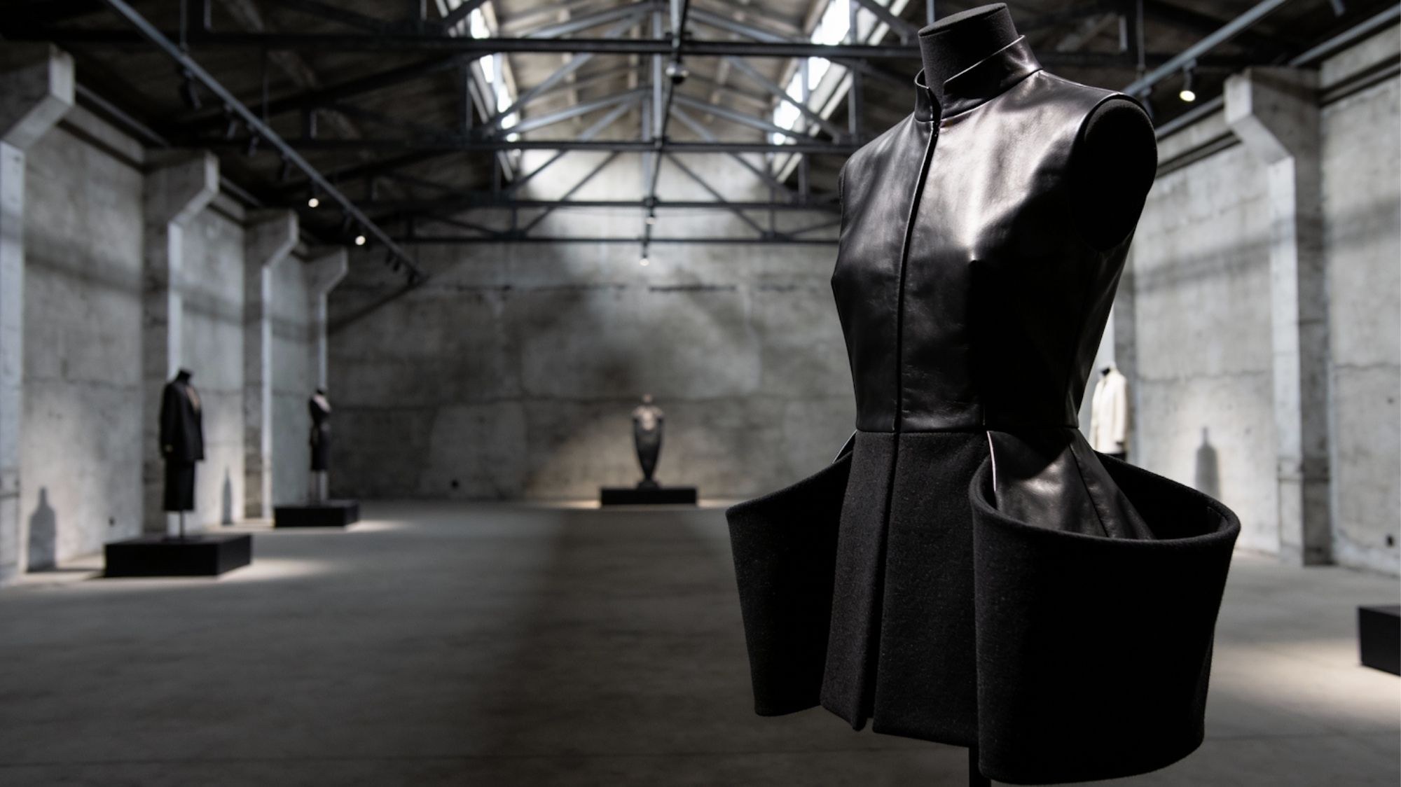 Avant-garde black sculptural dress displayed in an industrial architectural space, representing luxury Fashion Trend Forecasting, structured tailoring, and future runway aesthetics by C2 Fashion Studio.