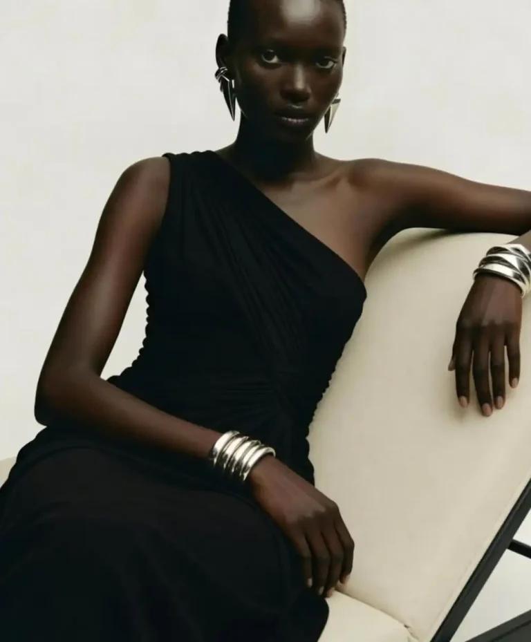 Minimal luxury fashion portrait featuring sculptural black draped eveningwear and metallic statement jewelry, representing strategic Fashion Trend Forecasting, quiet luxury, and Clarity Intelligence aesthetics by C2 Fashion Studio.