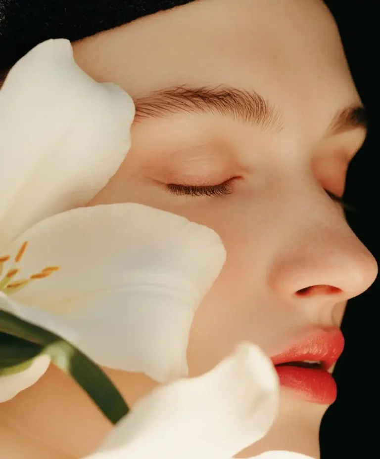Soft beauty portrait with white floral elements and natural glowing skin representing Future Consumer 2028 aesthetics focused on emotional wellbeing, sensory beauty, and conscious luxury by C2 Fashion Studio.