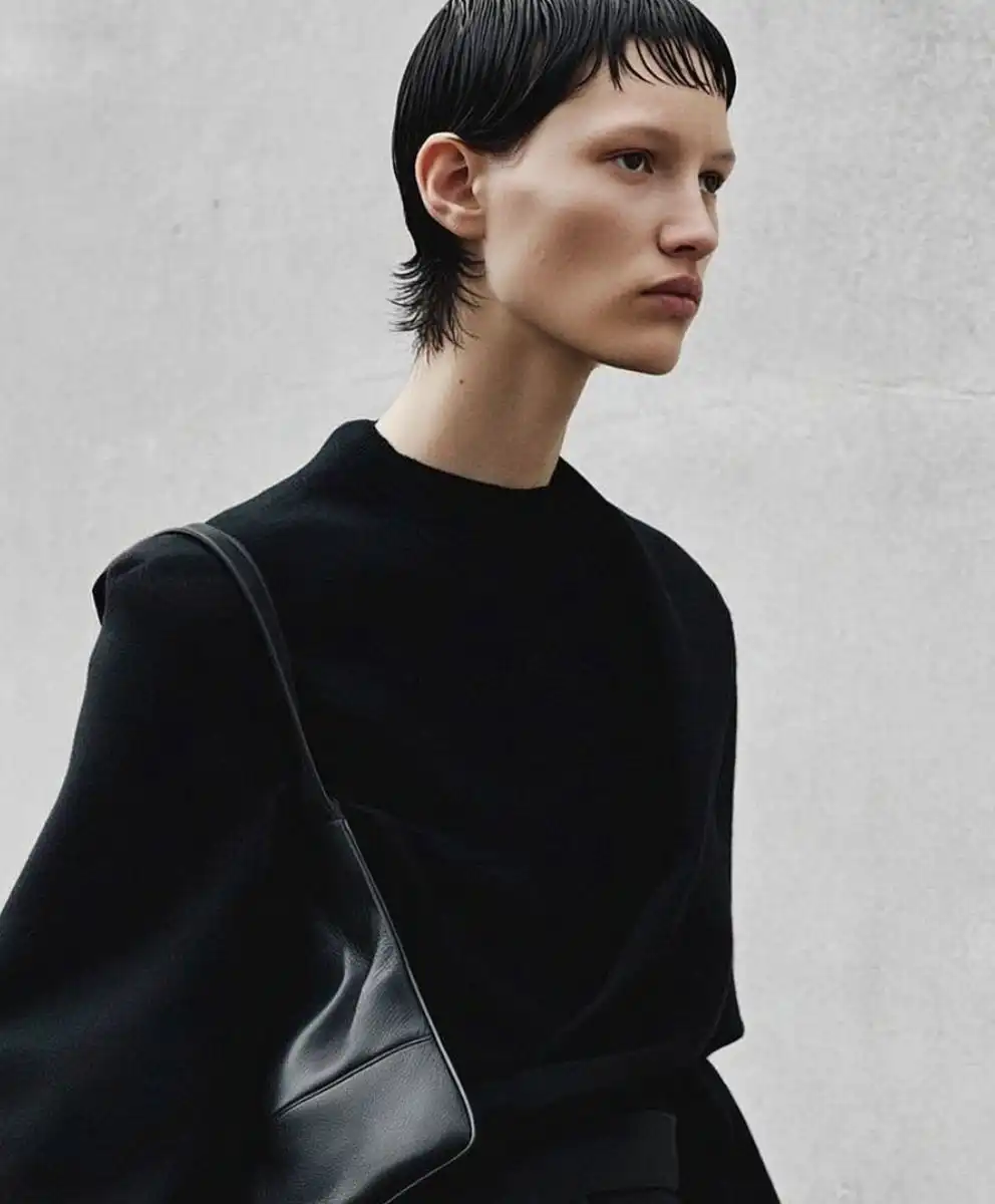 Minimalist fashion portrait featuring a model in a structured black silhouette with a sleek leather bag, reflecting contemporary luxury, quiet confidence, and emerging Fashion Trend Forecasting directions focused on refinement, simplicity, and intentional design.