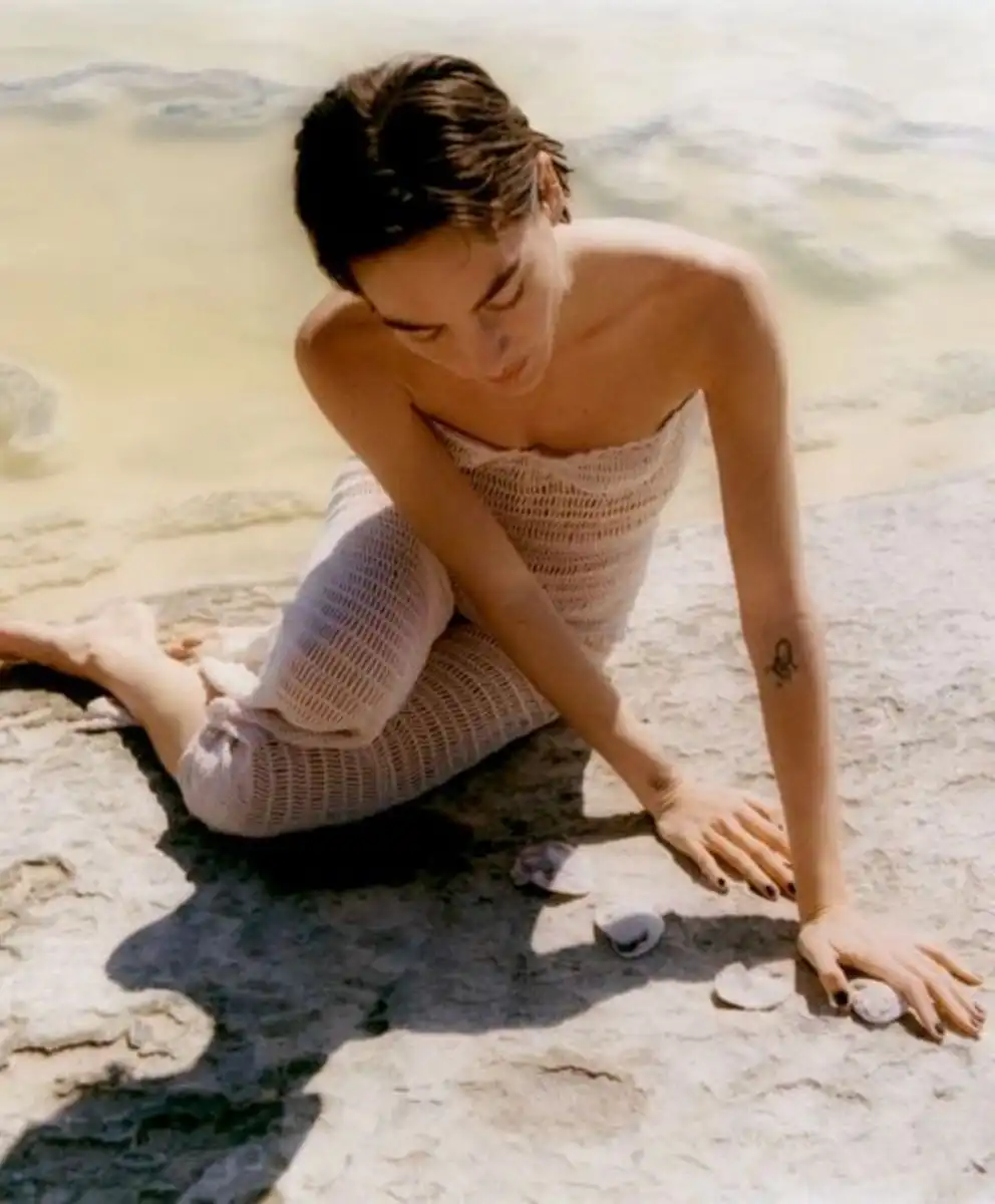 Luminous Balance Spring Summer 2028 Color Trend Forecast by C2 Fashion Studio featuring a model in a soft neutral open-knit ensemble beside mineral waters, expressing visual equilibrium, calm sophistication, natural textures, and contemporary luxury through Fashion Trend Forecasting, Trend Intelligence, Material Intelligence, and Consumer Behavior insights.