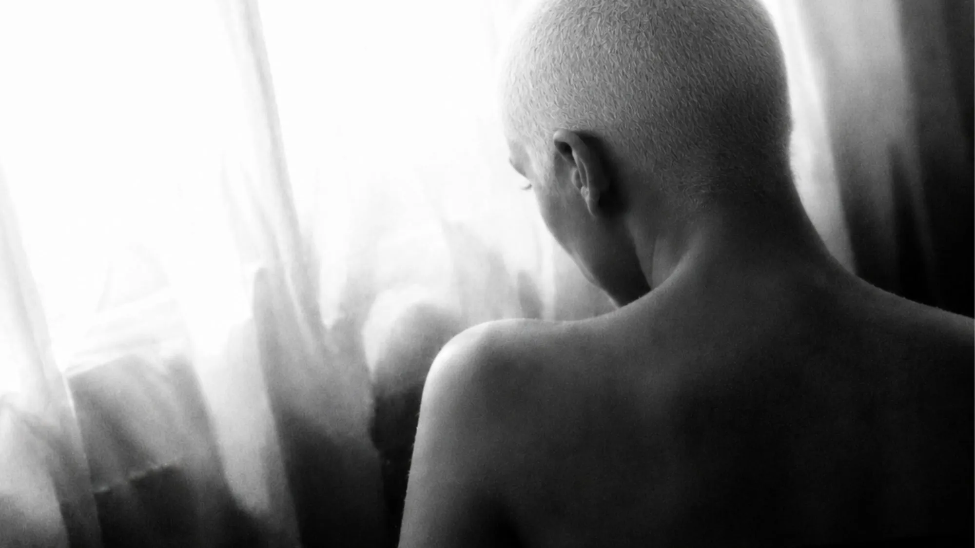 Black and white editorial portrait of a woman with a shaved head, exploring body and wellness trends, self-awareness, personal identity and lifestyle trend forecasting by C2 Fashion Studio.